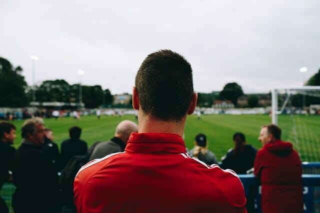 man standing while watching soccer